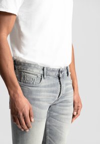 Lichtgrijze denim jeans met een slim fit, voorzien van een klassiek vijfzakkenontwerp, subtiele vervaging en een contrasterend stikseldetail.