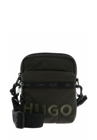Piccola borsa a tracolla verde scuro con tracolla nera regolabile e grande logo "HUGO" ricamato sulla tasca frontale.