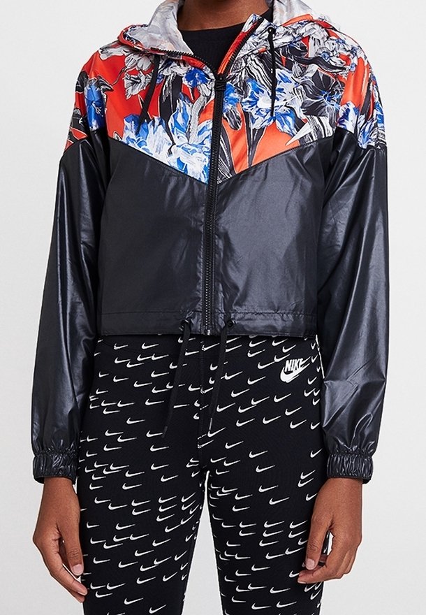 Lehká bomber bunda černé barvy s květinovým designem v červené a modré na kapuci, s uzávěrem na zip a stahovací spodní částí. V kombinaci s vzorovanými legínami.