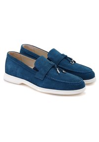 Blaue Wildlederslipper mit einer weißen Gummisohle, die über Nähte und eine dekorative Schleifenakzentuierung an der Vorderseite verfügen.