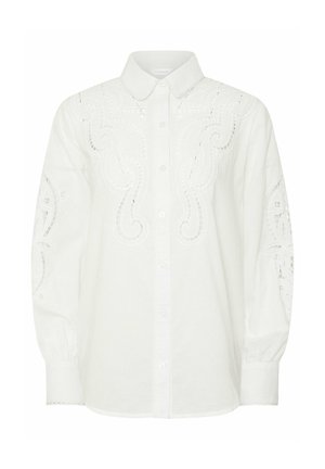 Blouse blanche à manches longues boutonnée avec motifs tourbillonnants découpés brodés sur le devant, les manches et le col, avec un col pointu et des poignets.