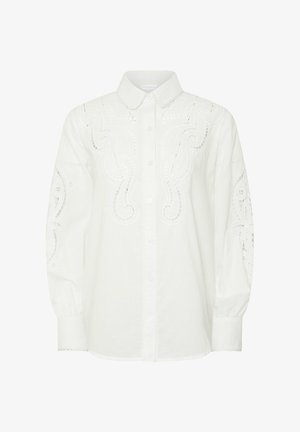 Blouse blanche à manches longues boutonnée avec motifs tourbillonnants découpés brodés sur le devant, les manches et le col, avec un col pointu et des poignets.