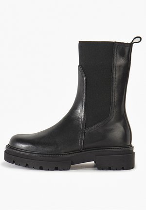 Bottine noire en cuir lisse et textile élastique. Elle est dotée d'une semelle épaisse avec une texture antidérapante et d'une languette à l'arrière.