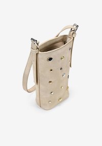 Bolso bandolera de imitación cuero beige con estrella metálica y tachuelas circulares, forma rectangular plana, correa ajustable y cierre con cremallera en la parte superior.