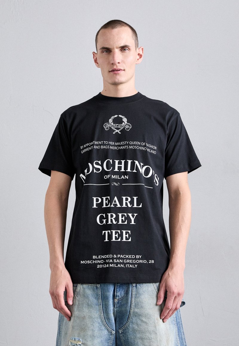 Juodas medvilnės marškinėliai su balta tekstu ir logotipu. Trumpomis rankovėmis ir apvaliu iškirpimu. Įtrauktos prekės detalės ir užrašas "PEARL GREY TEE".