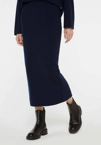 Navyblaue knöchellange Rock aus weichem Stoff, kombiniert mit schwarzen Lederstiefeletten mit einer stabilen Sohle und elastischen Seitenpanelen.