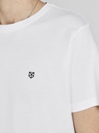 Weißes Baumwoll-T-Shirt mit rundem Halsausschnitt und kurzen Ärmeln. Kleines schwarzes Logo auf der linken Brustseite gestickt. Glatte Textur.