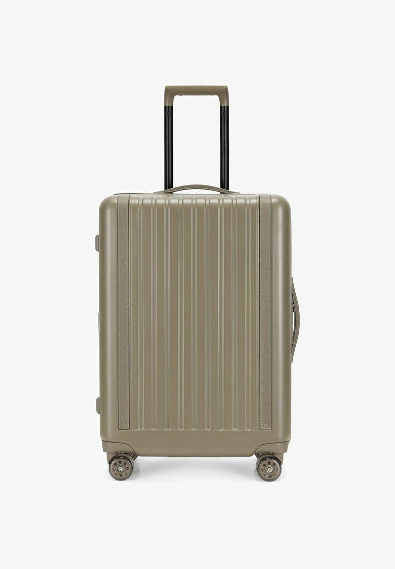 Valise rigide beige avec des rainures verticales, quatre roues, une poignée rétractable étendue, et des poignées latérales et supérieures.