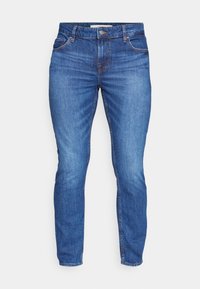 Siniset farkut, joissa on kapea istuvuus, viisi taskua, edessä vetoketju ja kontrastivärinen ompelu. Kankaan pinta on sileä ja siinä on hieno kiilto.