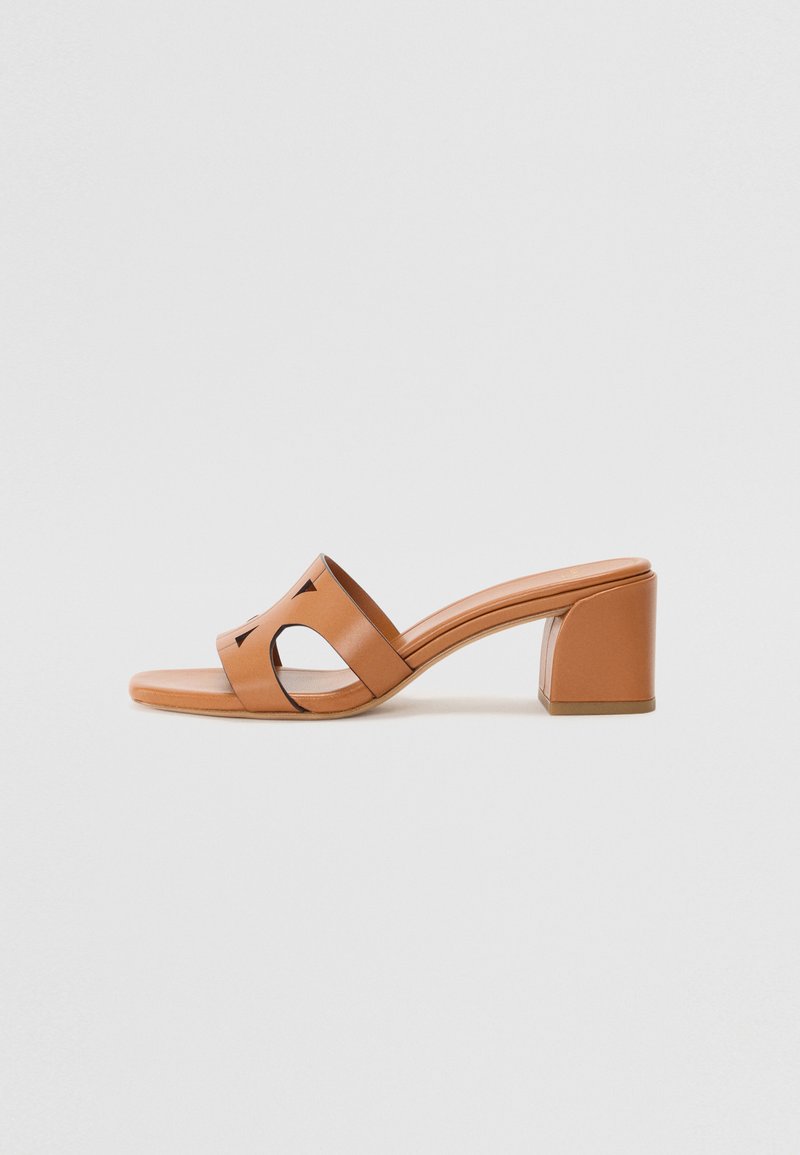 Tan lær hevede toft sandaler med blokhæle, åben tå og udskæringsdesign detaljer på remmen for ekstra visuel interesse.