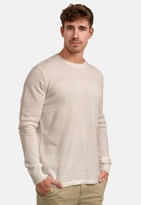 Világosbézs kötött pulóver texturált vízszintes csíkokkal, kerek nyakkivágással és bordázott mandzsettákkal. Testhez simuló szabású, hosszú ujjú.