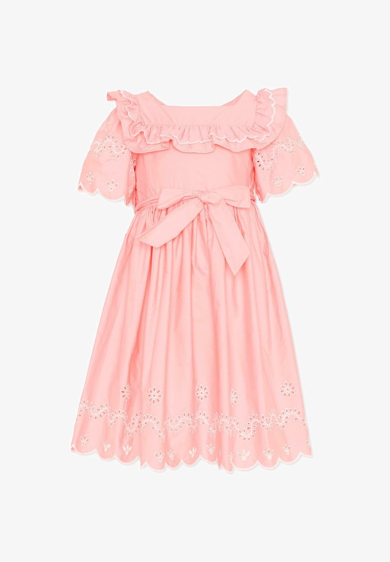 Roze knielange jurk met ruches langs de halslijn, opengewerkte borduursels op de mouwen en zoom, en een strik in de taille.