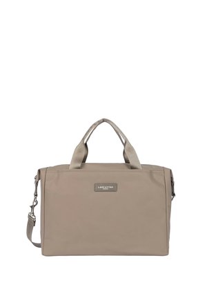 Sac rectangulaire beige Lancaster Paris avec double poignée supérieure et bandoulière latérale réglable, patch logo visible à l'avant.