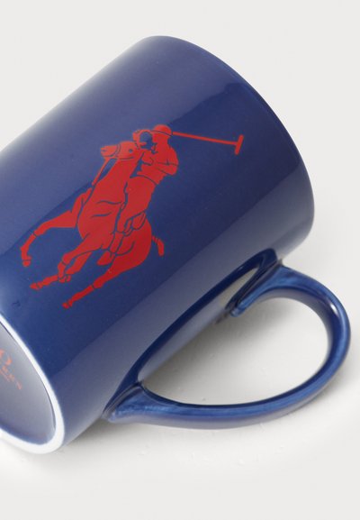Keramikkopp i marineblå med grafikk av en polo-spiller i rødt. Har et buet håndtak og glansfull finish, som viser detaljerte designelementer.