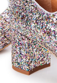 Scarpa con tacco alto adornata di glitter, con un tacco robusto, caratterizzata da paillettes multicolori su una superficie lucida e una base marrone liscia.