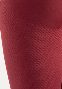 Rode atletische legging gemaakt van gestructureerde stof, met een diamantpatroon, een gladde afwerking en een aangesloten ontwerp voor optimaal comfort.