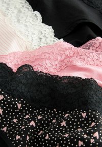Lingerie met kantafwerking in zwart, wit en roze. Kenmerkt zich door stippen en harten op de stof, met verschillende texturen en patronen.