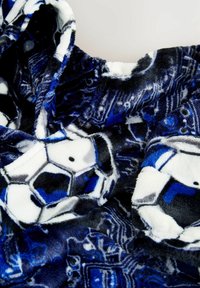 Fleece-Decke mit einem Muster aus blauen, schwarzen und weißen Fußballen, einem weichen, plüschigen Material und abstrakten Designs im Hintergrund.