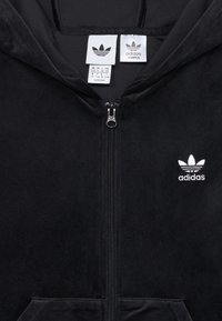 Black zip-up hoodie made of soft material. Features a silver zipper, front pockets, and white embroidered Adidas logo on the left chest.