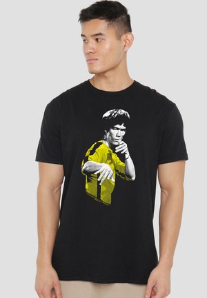 Black T-shirt featuring a graphic of a person in gray and yellow, showcasing short sleeves and a crew neck design.