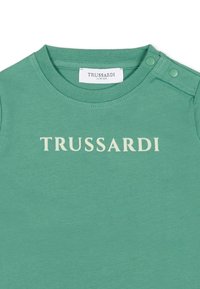 T-shirt in cotone verde con scollo rotondo, chiusura a bottoni a pressione sulla spalla e logo "TRUSSARDI" in testo color crema.