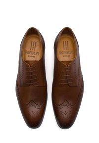 Scarpe da dress in pelle marrone con finitura liscia, design wingtip e dettagli perforati. Presentano lacci e logo impresso sulla soletta.