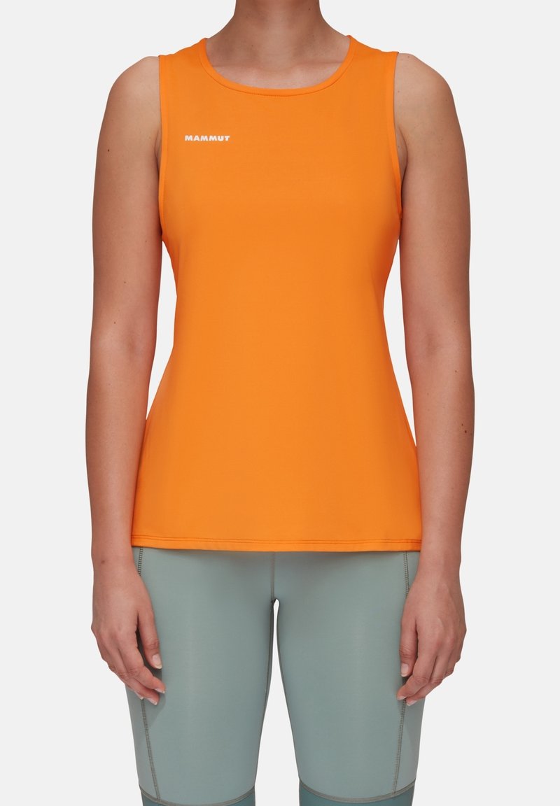 Femme portant un haut de sport sans manches orange vif avec le logo "Mammut" et des leggings de sport ajustés gris clair.