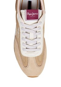 Beigen värinen lenkkari, jossa on mokkanahka- ja sileän nahkan tekstuureja, vaalean värinen kielen osa, litteät nauhat ja viininpunainen logoplässi.