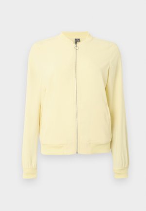 Giacca bomber gialla con chiusura a zip, polsini e orlo a costine e collo rotondo. Realizzata in tessuto liscio con una texture leggera.