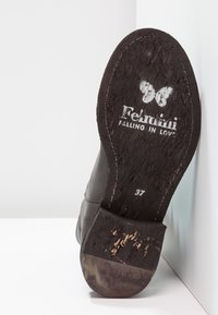 Czarne skórzane buty z teksturowaną podeszwą, z nadrukowanym logo i rozmiarem "37". Podeszwa nosi ślady użytkowania, co podkreśla jej eksploatację.