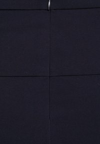 Tissu bleu marine foncé présentant un design tissé texturé avec des lignes de couture visibles et une fermeture éclair en métal en haut.