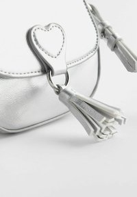 Borsa in pelle sintetica argento con chiusura a forma di cuore, zip con nappina e finitura testurizzata con dettagli di cucitura visibili.