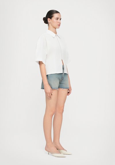Korte mouw witte blouse met een kraag, gecombineerd met denim shorts. De blouse heeft een rechte snit en knopen aan de voorkant.