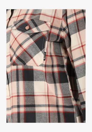 Kariertes Hemd mit Brusttasche und Knopfklappe in Beige, Schwarz und Rot, mit kleinem schwarzem Stoffetikett am Taschenrand.