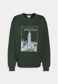 Sudadera de color verde oscuro con un gráfico en blanco del Edificio Chrysler y el texto "NUEVA YORK". Cuello redondo clásico y puños acanalados. Textura de tela suave.