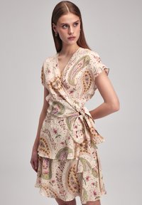 Wickelkleid aus leichtem Creme-Stoff mit floralen und Paisleymustern in Rosa und Grün. Volantsaum und Bindeband in der Taille. kurze Ärmel.