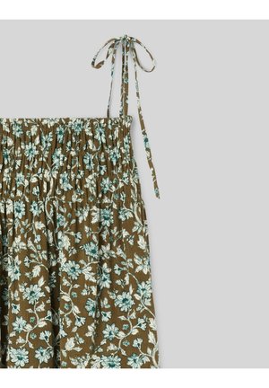 Tissu marron à motif floral blanc et vert, haut élastique froncé, et fines bretelles nouées aux épaules sur un fond gris.