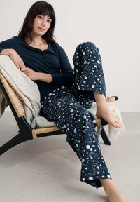 Námořnické pyžamo skládající se z dlouhého rukávu a kalhot s motivem měsíců, hvězd a květinových akcentů. Jemná látka; volný střih.