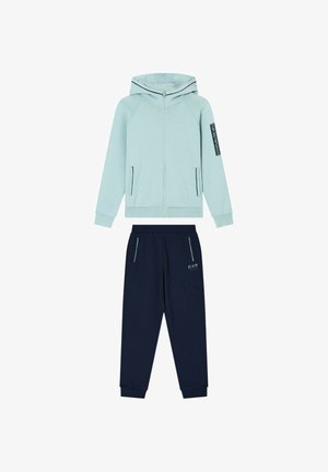 Felpa azzurro chiaro con cerniera e cappuccio, con dettagli neri, abbinata a pantaloni blu scuro con un logo. Entrambi sono realizzati in tessuto morbido.
