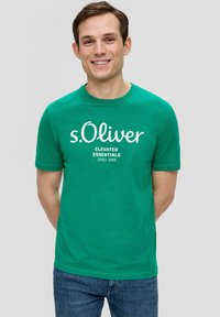 Groene katoenen t-shirt met een ronde hals, korte mouwen, en witte bedrukte tekst met de tekst "s.Oliver Elevated Essentials Since 1969."