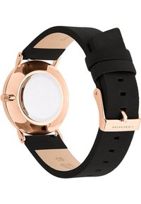 Roze-gouden metalen horlogekast met een zwarte siliconestrap. Beschikt over een gladde, gepolijste afwerking en een minimalistisch ontwerp. Transparante horlogeglas.