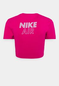 Krátký růžový crop top vyrobený z bavlněné směsi s nápisem "NIKE AIR" vytištěným na zádech bílým písmem tučnými, kontrastními písmeny.
