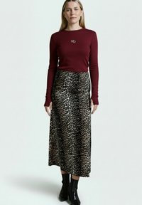 Burgunderfarbener Langarm-Top mit gerippter Textur, kombiniert mit einem Maxirock im Leopardenmuster. Schwarze Ankle Boots runden das Outfit ab.