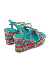 Sandales compensées turquoise avec une semelle intermédiaire tressée multicolore et des brides autour de la cheville. Tissu texturé et design à bout ouvert. Avec une fermeture à boucle.