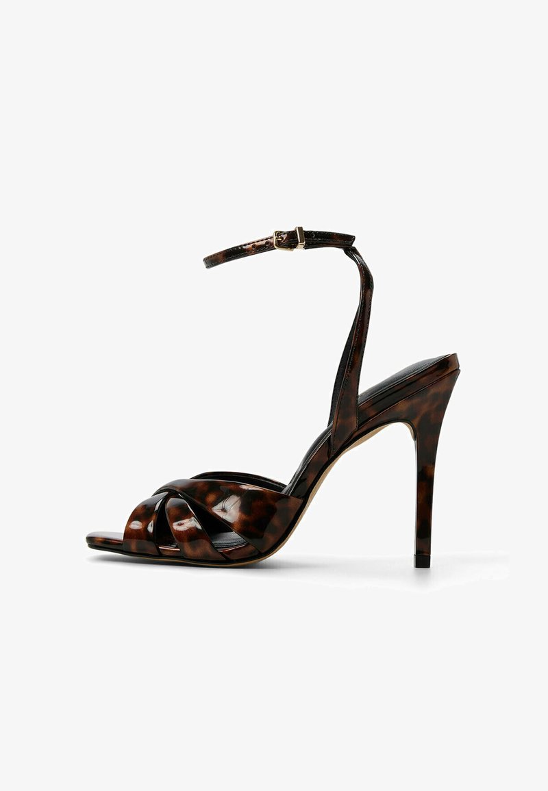 Bruin en zwart luipaardprint hoge hak sandaal met enkelbandje, open teen, en ineengestrengeld ontwerp aan de voorkant. Glad gepatineerd leer.