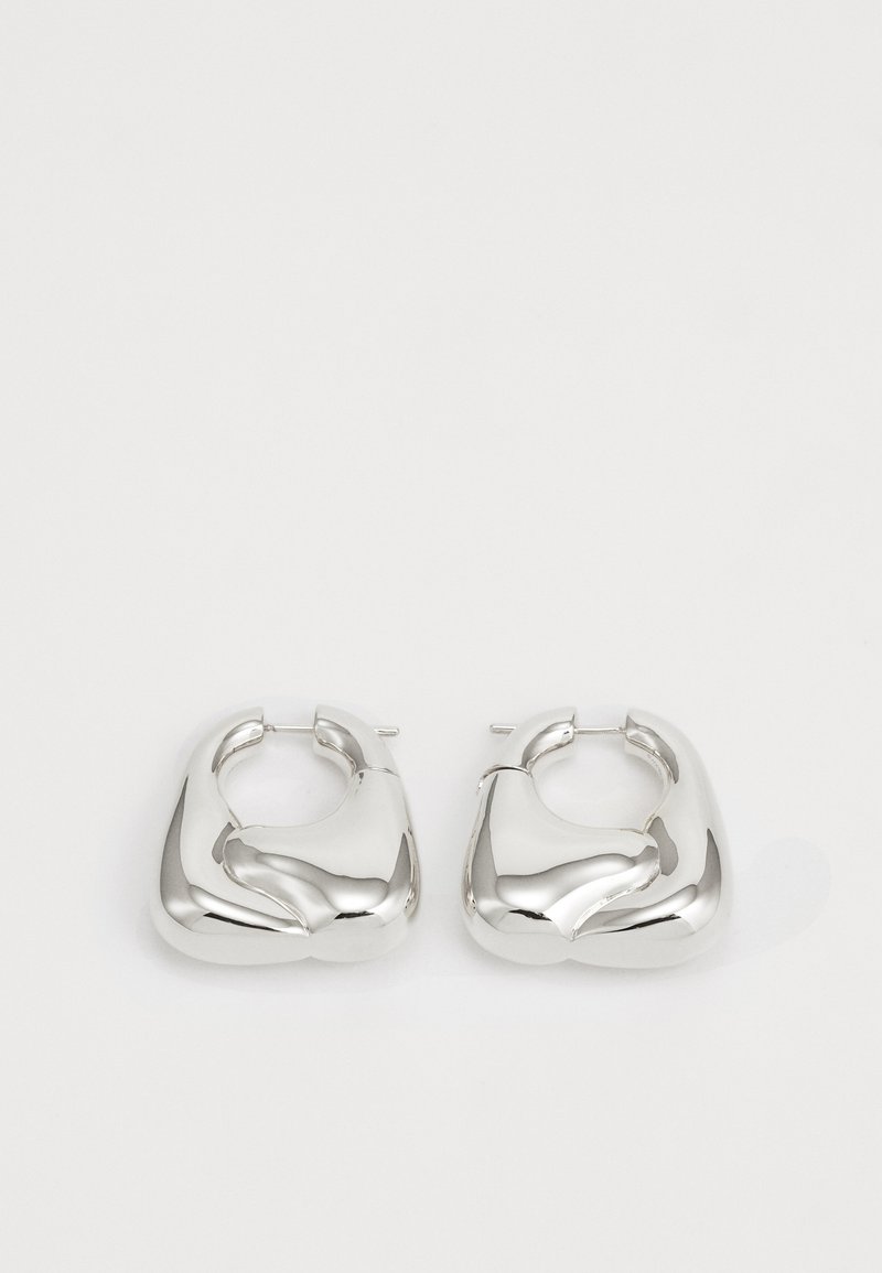 Sudraba riņķi auskari ar gludu, skulpturālu dizainu, kuriem ir kvadrāta forma ar pulētu, atstarojošu apdari.