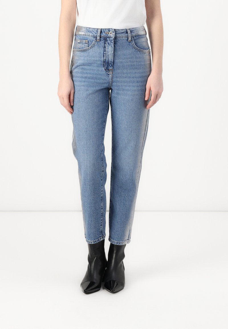 Lys blå denimjeans med en litt innsnevret passform, fem-lommers design, høy midje og subtil falming. Kombinert med svarte ankelstøvler.
