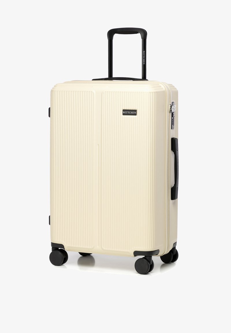 Harde koffer in crème met een textuur met ribbelontwerp, zwarte wielen en handvat. Voorzien van een rits en een klein logo aan de voorkant.