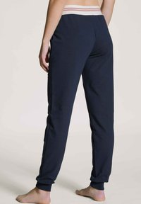 Marineblauwe sweatpants met een gestreepte elastische tailleband, taps toelopende benen en een zachte textuur. Heeft zijnaad en geribde manchetten.