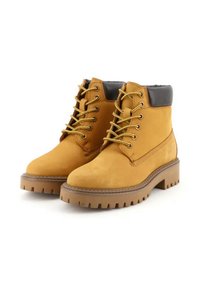 Stivaletti alla caviglia in suede marrone con punta arrotondata, lacci gialli e bordo imbottito nero; dotati di una suola in gomma spessa con un motivo a tasselli.